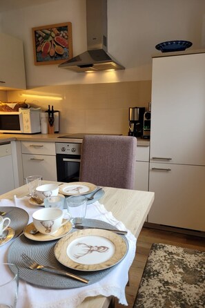 A kitchen with a dining table set for four, equipped with a microwave, coffee maker, and a range hood. - Zuppinger by Interhome (Mayrhofen)