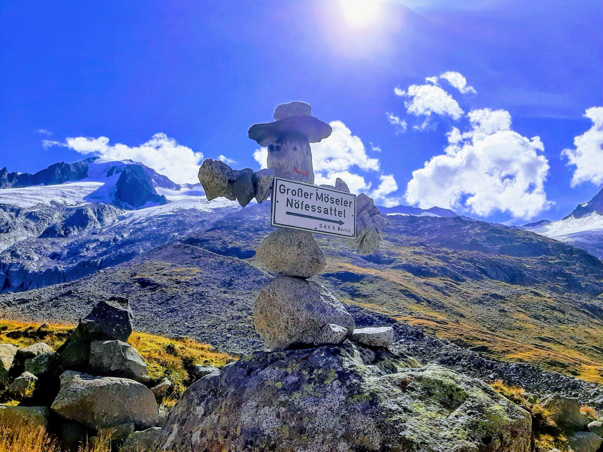 Un paysage de montagne avec un panneau indiquant « Großer Möseler Nöfelsattel » et un ciel dégagé.