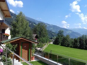 Une vue sur la montagne avec une maison et une petite construction en bois.
