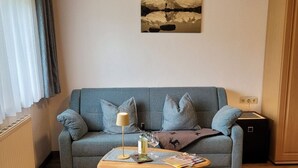 A living room with a sofa, a coffee table, a lamp, and a painting on the wall. - Zuppinger by Interhome (Mayrhofen)