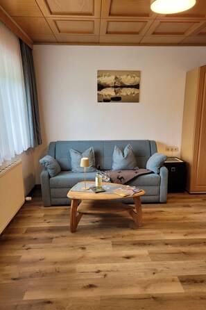 A living room with a sofa, a coffee table, a lamp, and a painting on the wall. - Zuppinger by Interhome (Mayrhofen)