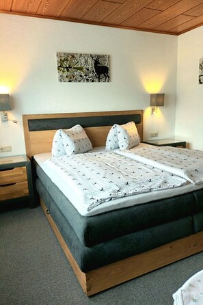 A bedroom with a wooden bed frame, two bedside tables, a wall-mounted lamp, and a painting. - Zuppinger by Interhome (Mayrhofen)