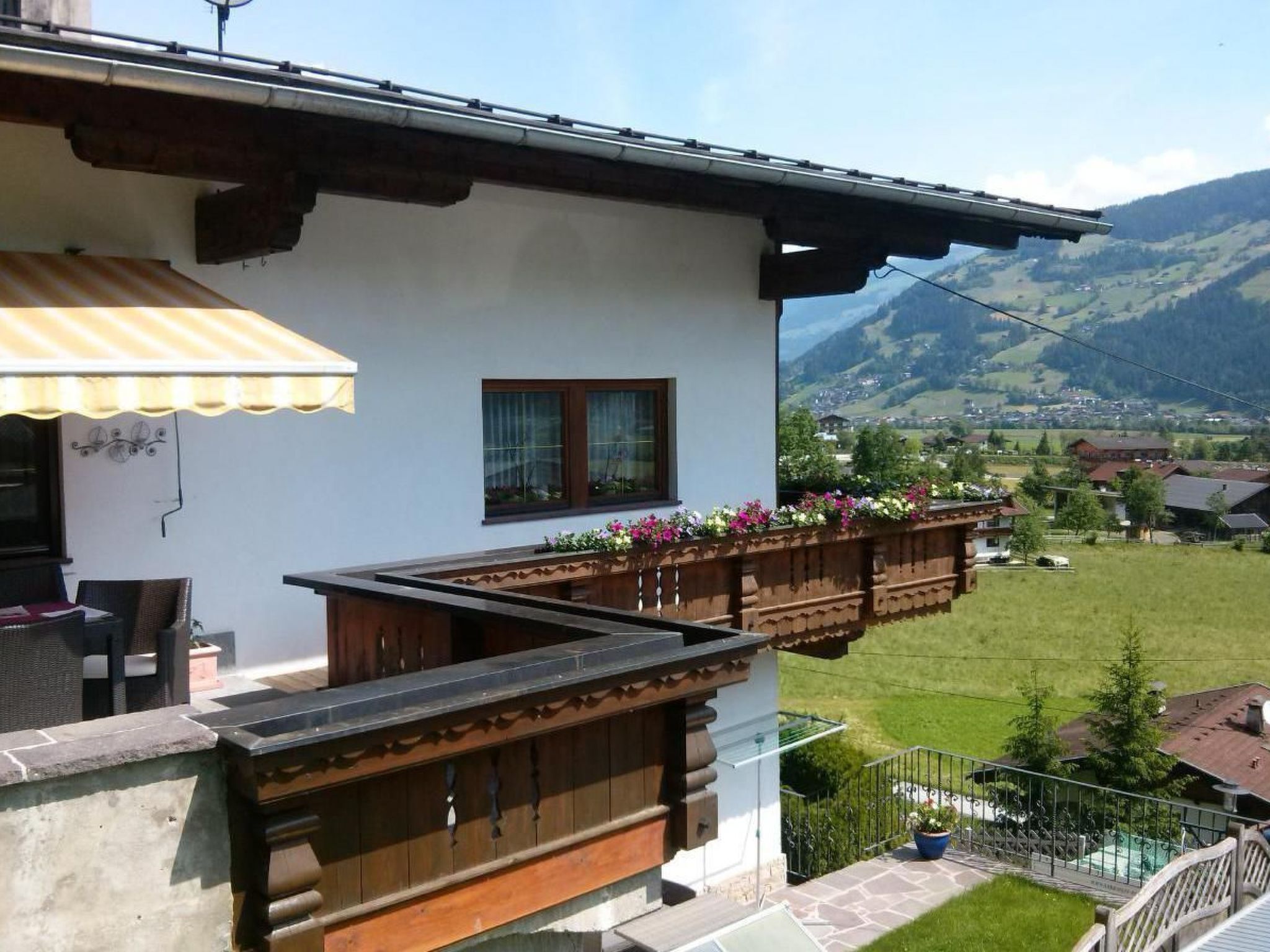 A house with a balcony overlooking a green landscape and mountains.