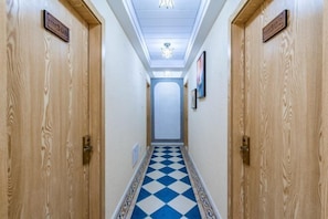 A hotel hallway with wooden doors, a checkered floor, and a ceiling light. - Shengsi Blue Bank Bieguan Homestay (Shengsi)
