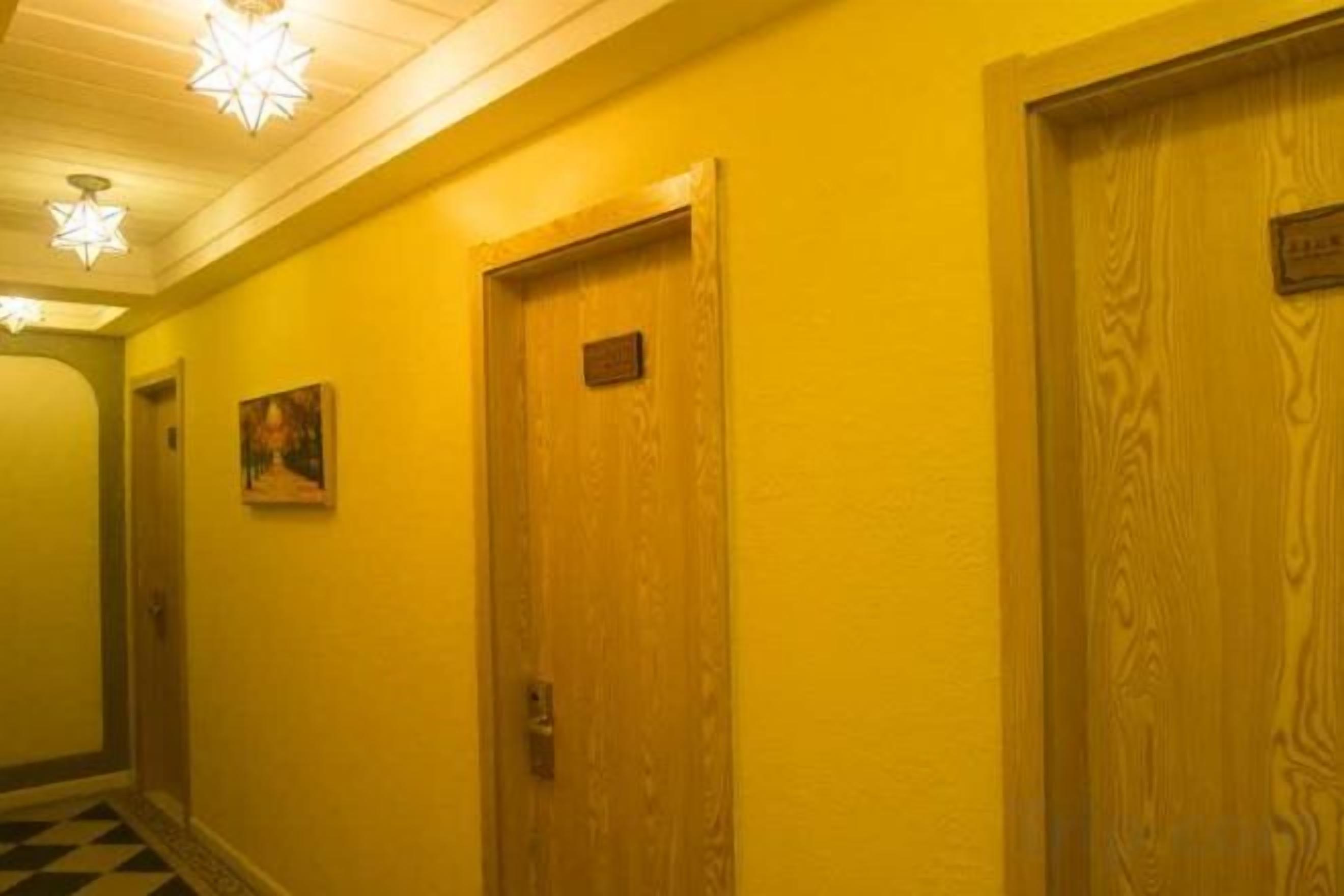 A hallway with wooden doors and a checkered floor.