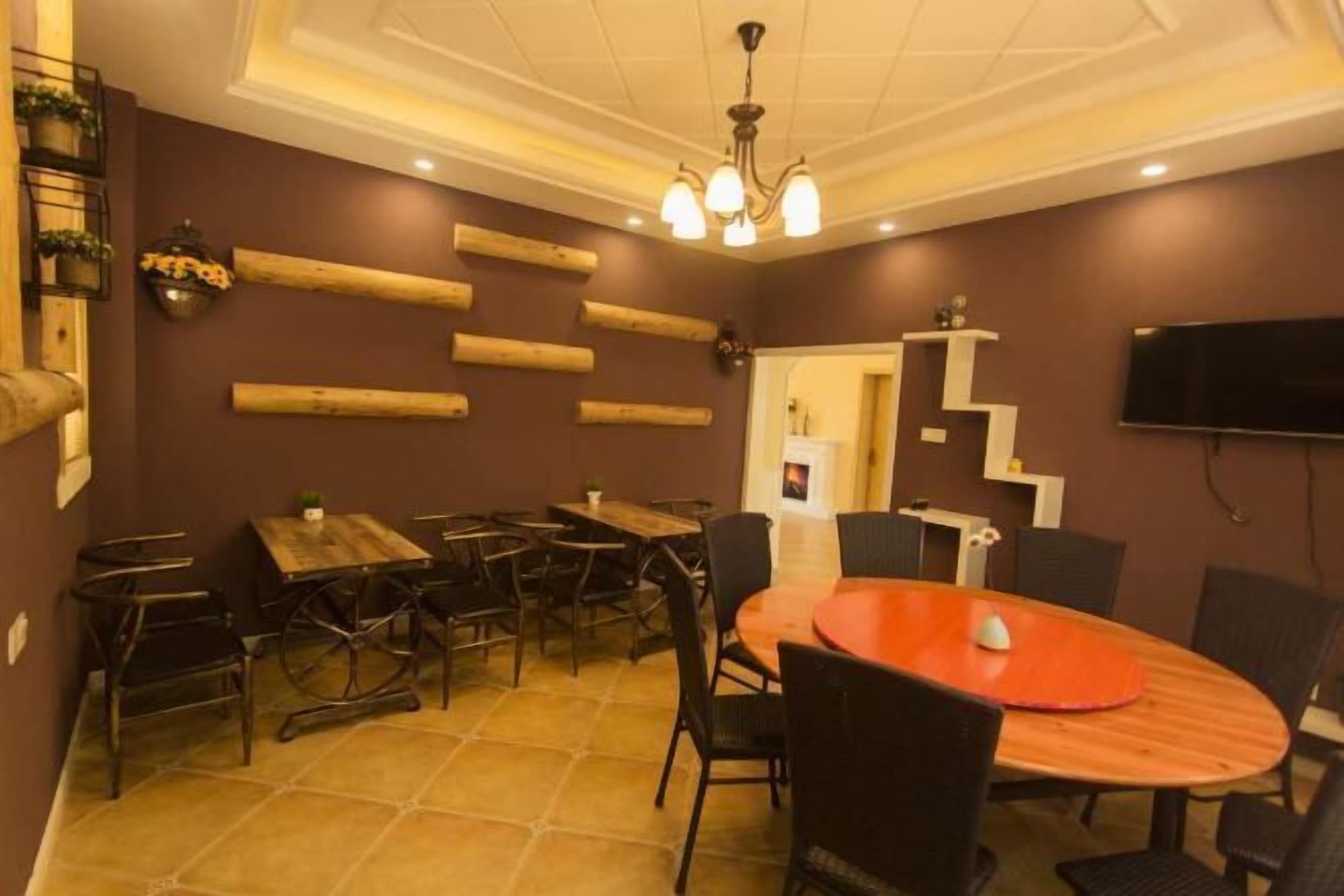 A dining area with a round table, multiple chairs, and a television mounted on the wall.