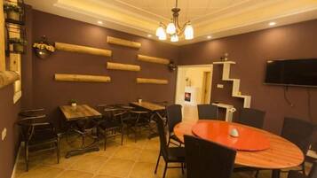 A dining area with a round table, multiple chairs, and a television mounted on the wall.