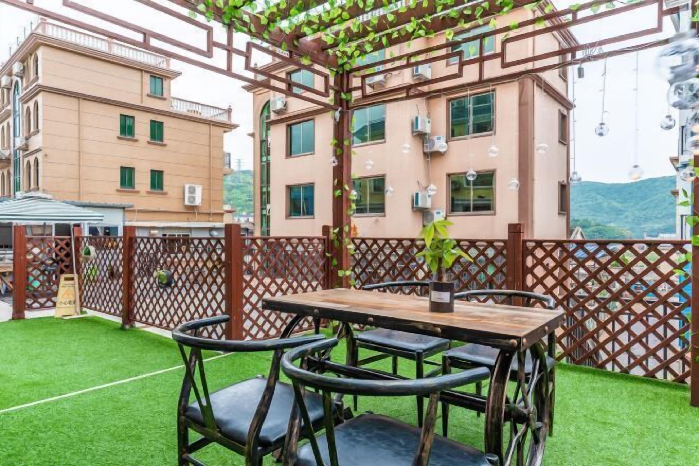 An outdoor seating area with a table and chairs, surrounded by a wooden fence and greenery.