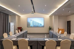 A conference room with a long table, chairs, a projector screen, and a podium. - Suzhou Yuanqu Xinghai SCHOLARS Hotel (Jinji Lake) (Suzhou)