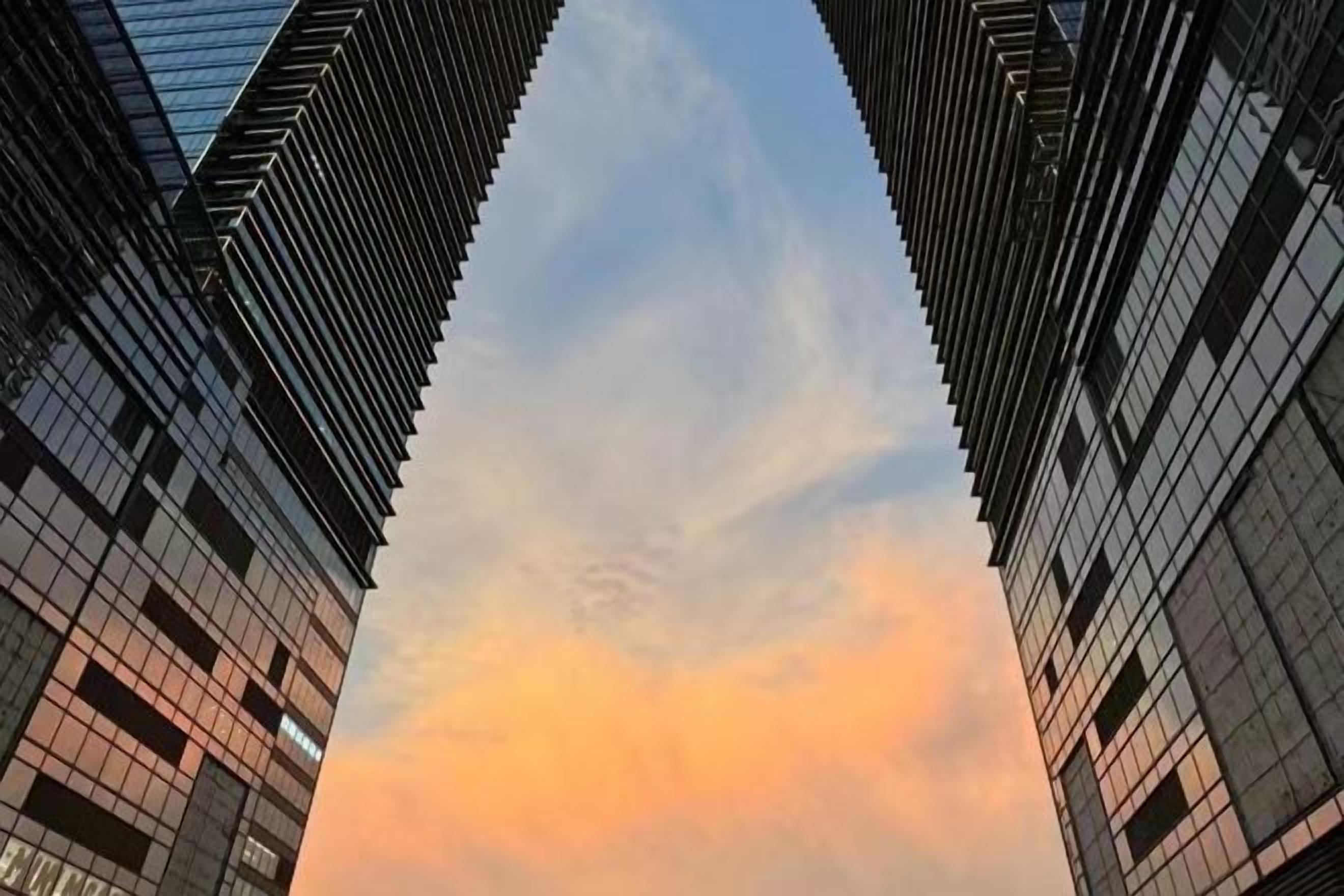 A view of tall buildings with a clear sky and a sunset.