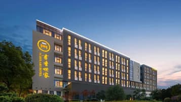 A modern hotel building with multiple floors, large windows, and a prominent logo on the facade.