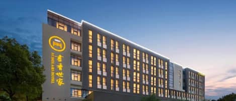 A modern hotel building with multiple floors, large windows, and a prominent logo on the facade.