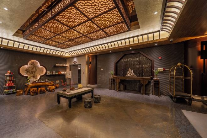 A spacious lobby with a high ceiling, a central table, and a decorative wall.