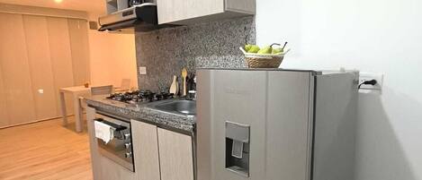 A modern kitchen with a built-in gas stove, stainless steel appliances, and a small refrigerator.