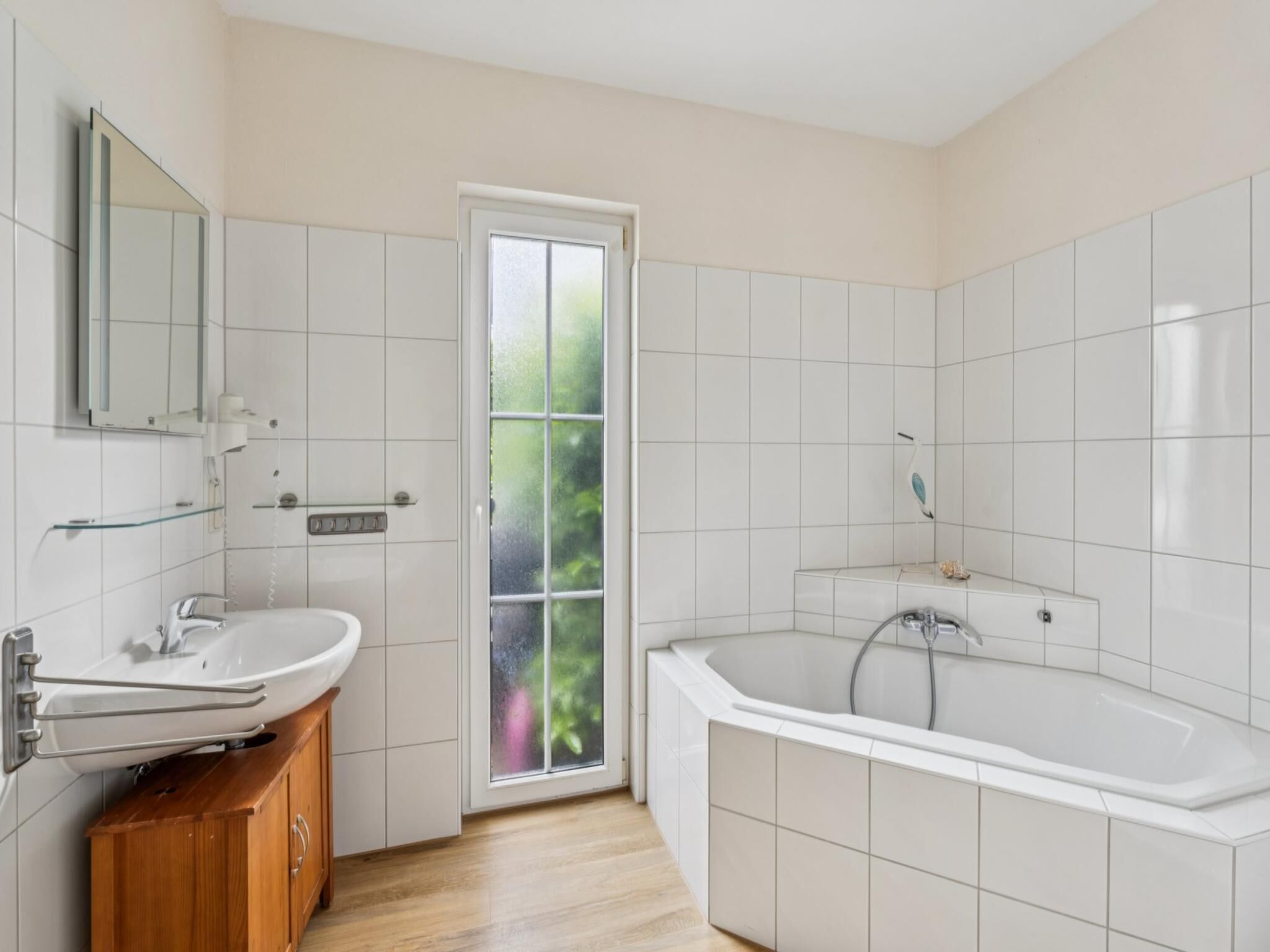 A modern bathroom with a white sink, vanity, and bathtub.
