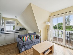 Eine moderne Küche mit Essbereich, einem Sofa mit bunten Kissen und einer großen Schiebeglastür, die auf eine Terrasse im Freien führt.
