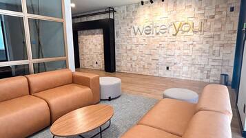 Un interior moderno con un sofá modular, una mesa redonda de madera y una pared con diseño de piedra que incluye la señalización 'welteryou'.