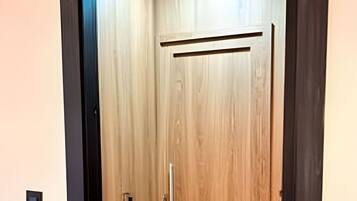 Una puerta de madera con un picaporte, un ventanal pequeño y un interruptor de luz en la pared.