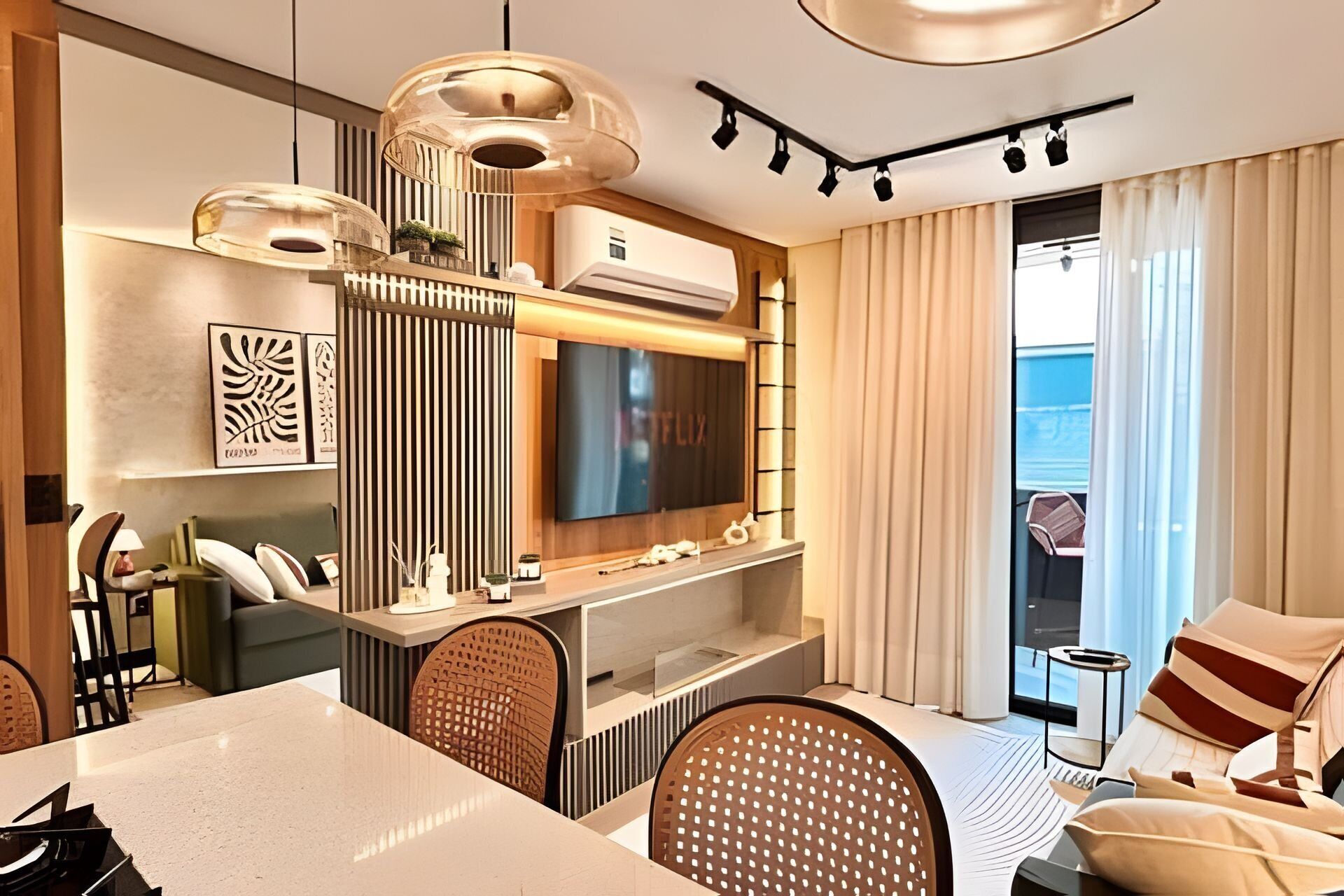 A modern living room with a flat-screen TV, a dining area with a white table, and a seating area with a sofa and chairs.