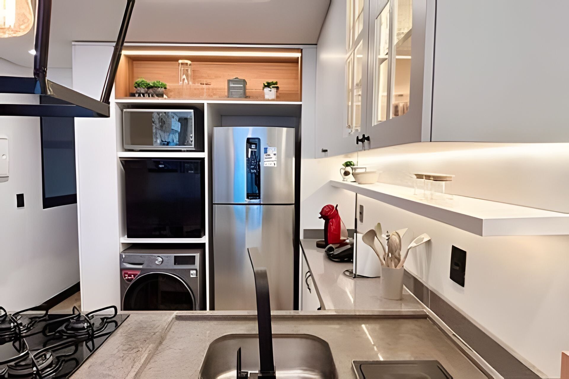 A modern kitchen with a built-in oven, a stainless steel refrigerator, and a gas stove.