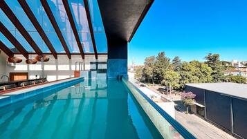 An indoor swimming pool with a view of the cityscape.