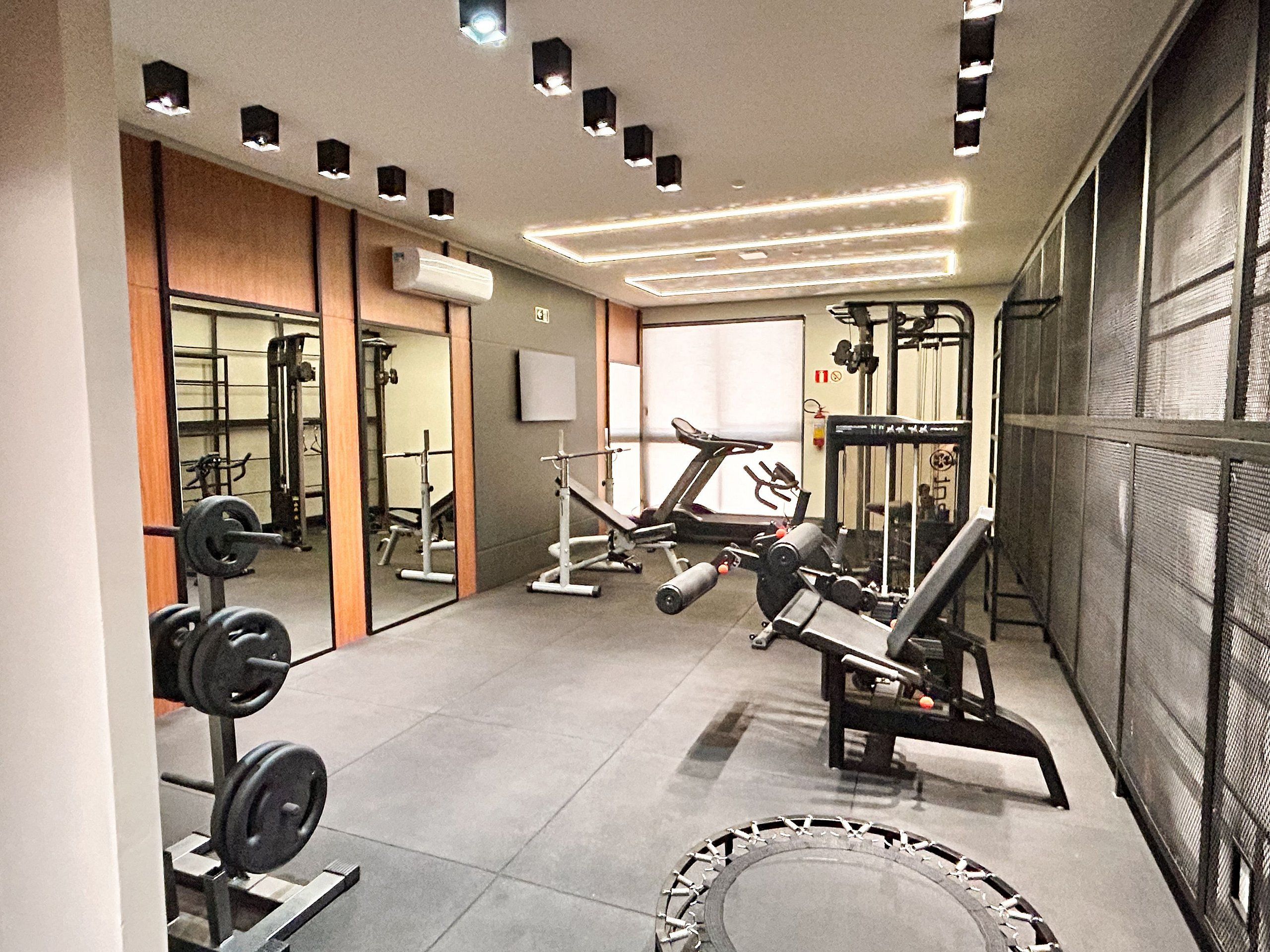 A gym with various exercise equipment, including a treadmill, weight bench, and free weights.