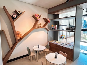 A room with a unique wooden shelf structure, a small table with chairs, and a window with a view.