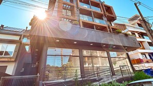 A multi-story building with balconies, large windows, and a visible sun.