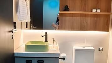 A modern bathroom with a sink, toilet, and wooden shelves.