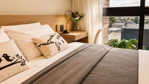A neatly made bed with a grey blanket, a wooden headboard, and decorative pillows with bird designs.