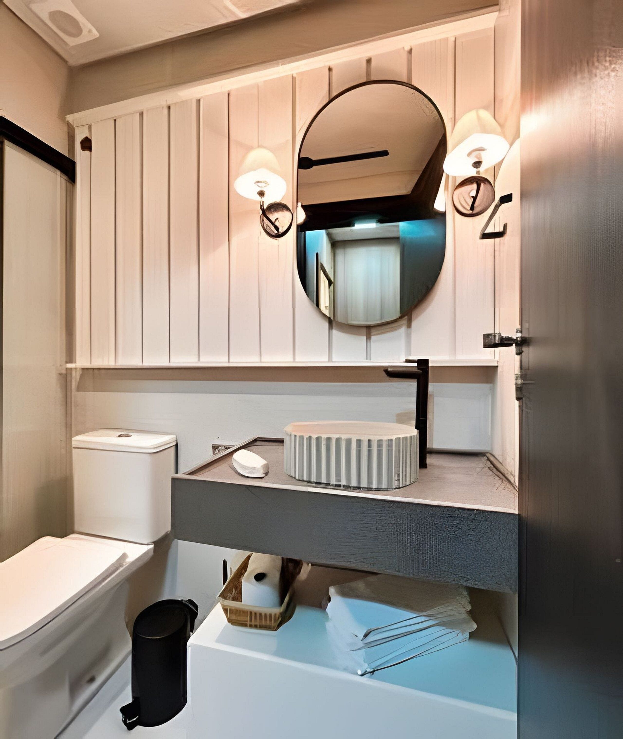 Un baño moderno con inodoro, lavamanos y espejo.