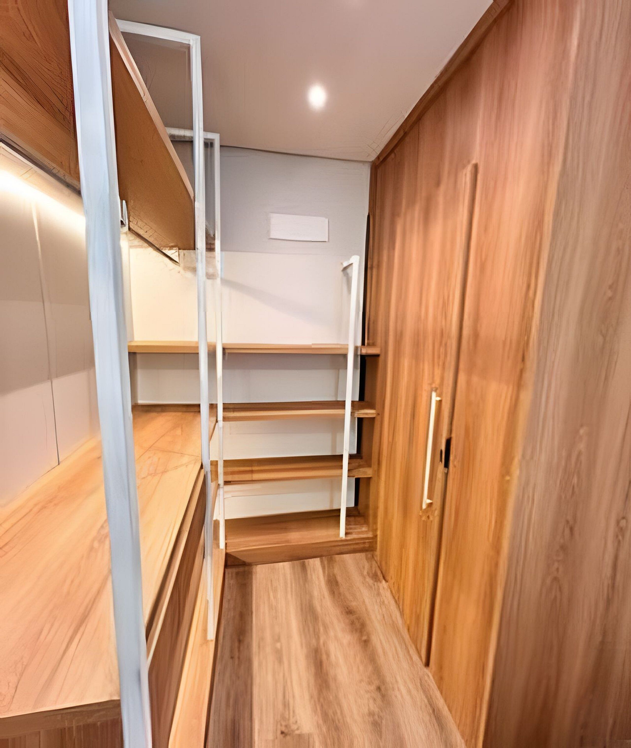 Een inloopkast met houten vloeren, witte schapenkasten en een houten garderobe.