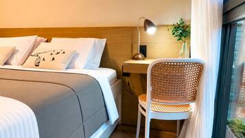 A neatly arranged hotel room with a bed, a desk, a chair, and a window.