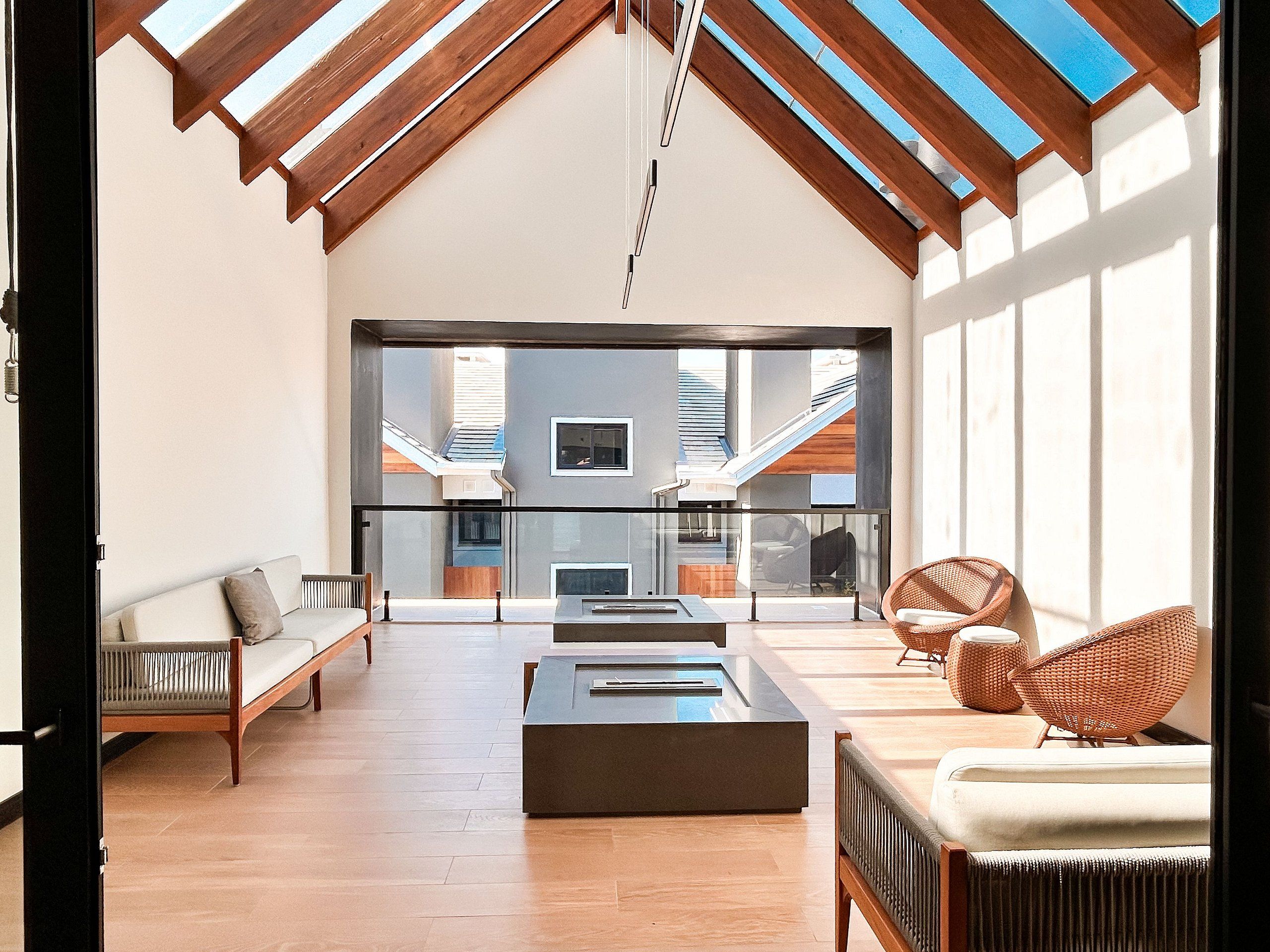 A spacious living area with a high ceiling, a fireplace, and a view of a staircase leading to an upper level.