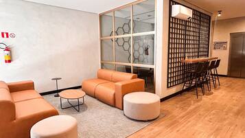 Un interior moderno con sofá, reposapiés y un comedor con sillas y mesa.