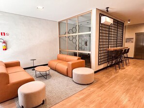 A modern interior with a sofa, ottoman, and a dining area with chairs and a table.