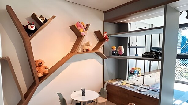 A room with a unique wooden shelving unit, two round tables, and chairs.
