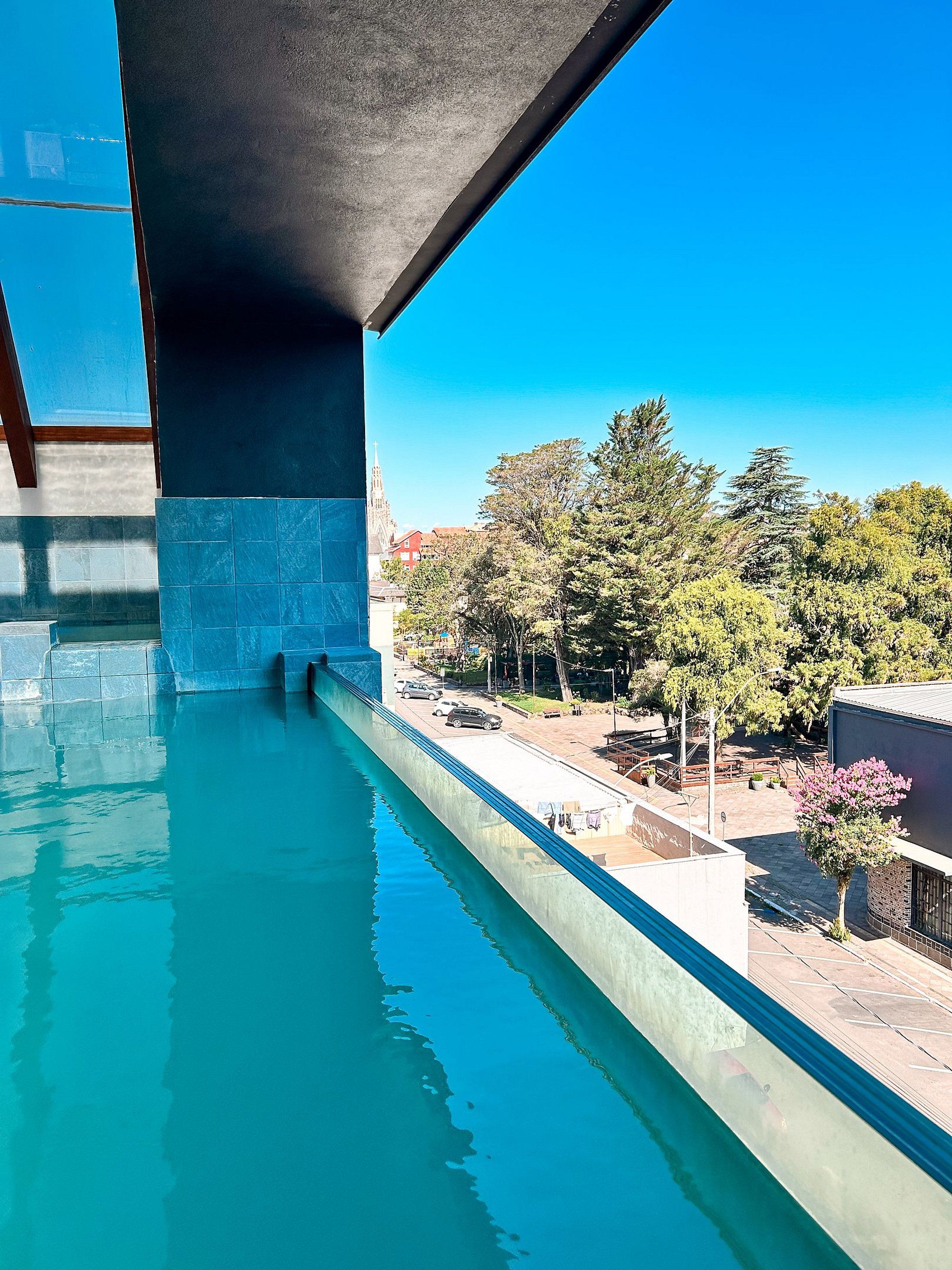 Una piscina con vistas a árboles y edificios bajo un puente.