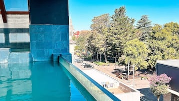 Una piscina con vistas a árboles y edificios bajo un puente.