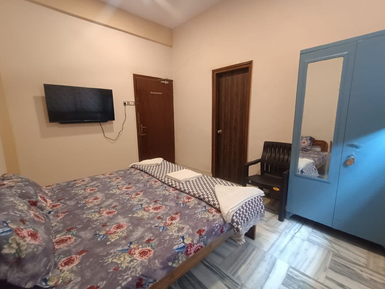 Un dormitorio con cama, armario, silla y televisión en la pared.
