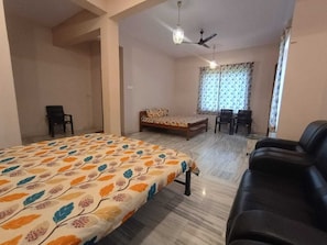 A bedroom with a bed, a sofa, a desk, and a ceiling fan.