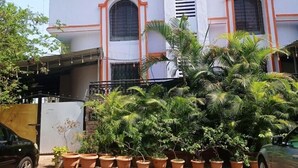 A two-story building with a central staircase, surrounded by potted plants.