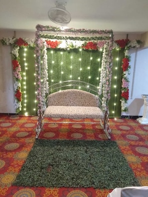 A room with a patterned carpet, a decorative chair, and a floral backdrop with string lights.