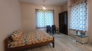 A bedroom with a bed, a ceiling fan, a desk, and two chairs.
