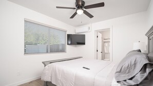 A bedroom with a bed, a ceiling fan, a TV mounted on the wall, and a window with blinds. - Spacious high-end, newly remodeled 5-bedroom house in delightful Gilbert. (Gilbert)