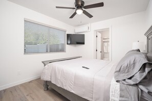 A bedroom with a bed, a ceiling fan, a TV mounted on the wall, and a window with blinds. - Spacious high-end, newly remodeled 5-bedroom house in delightful Gilbert. (Gilbert)