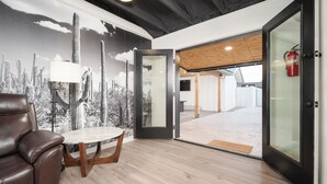 A modern interior with a leather chair, a round table, and a mural of cacti. - Spacious high-end, newly remodeled 5-bedroom house in delightful Gilbert. (Gilbert)