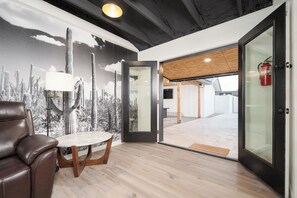 A modern interior with a leather chair, a round table, and a mural of cacti. - Spacious high-end, newly remodeled 5-bedroom house in delightful Gilbert. (Gilbert)