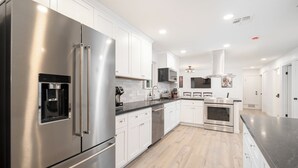 A modern kitchen with stainless steel appliances, white cabinetry, and a wooden floor. - Spacious high-end, newly remodeled 5-bedroom house in delightful Gilbert. (Gilbert)