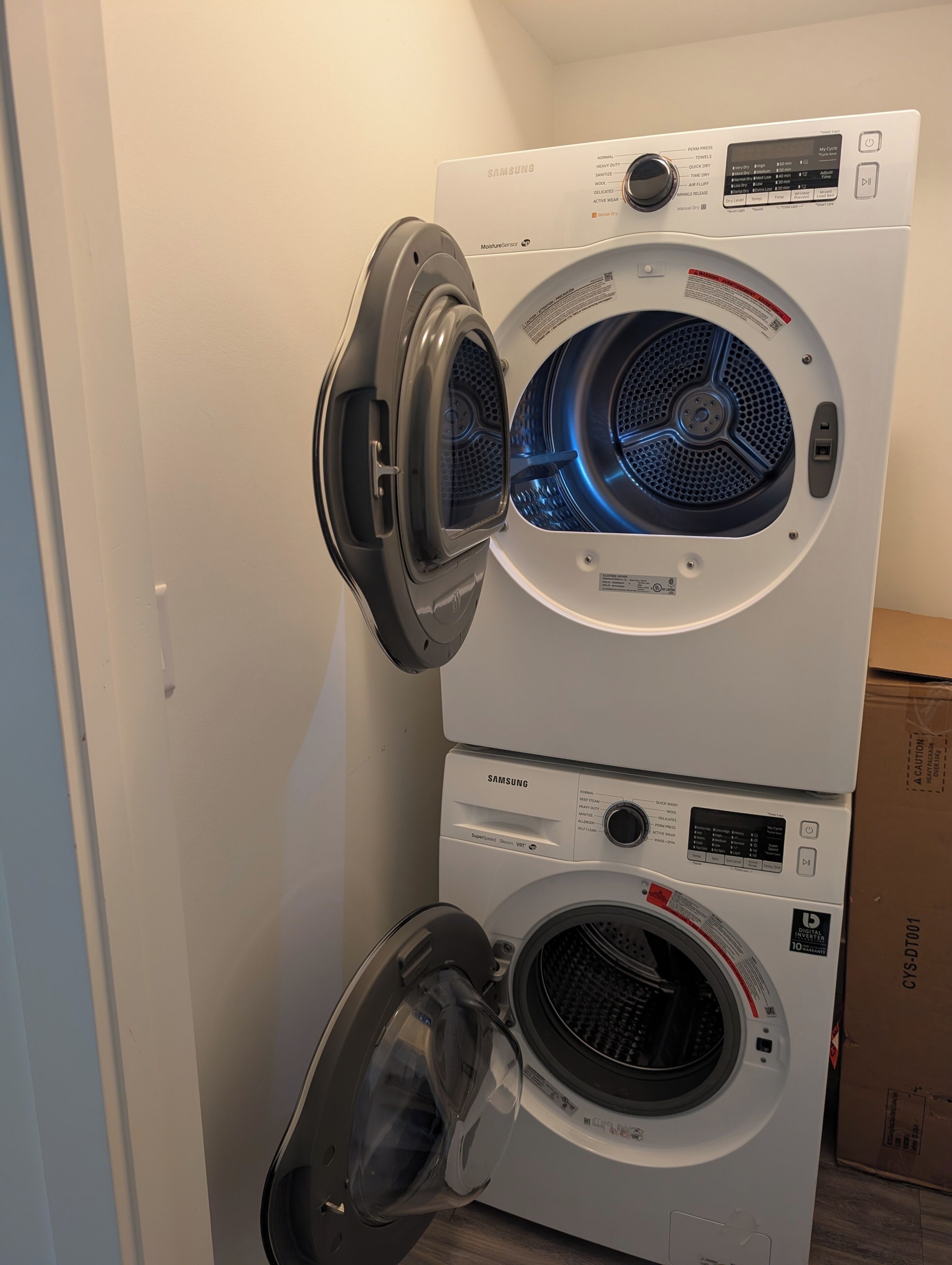 A stacked washer and dryer unit with a digital control panel, a moisture sensor, and a digital inverter label.